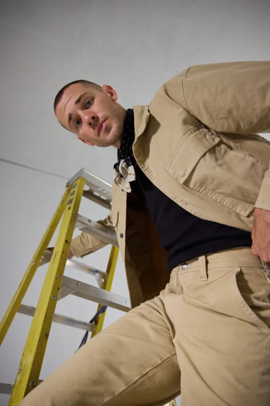 Fashion photo of male model in navy loose-fit pants and vest styled in minimalist studio for menswear shoot.