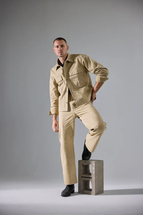 Male model with tattoos in a navy vest, captured in a studio setting for fashion ecommerce portfolio.