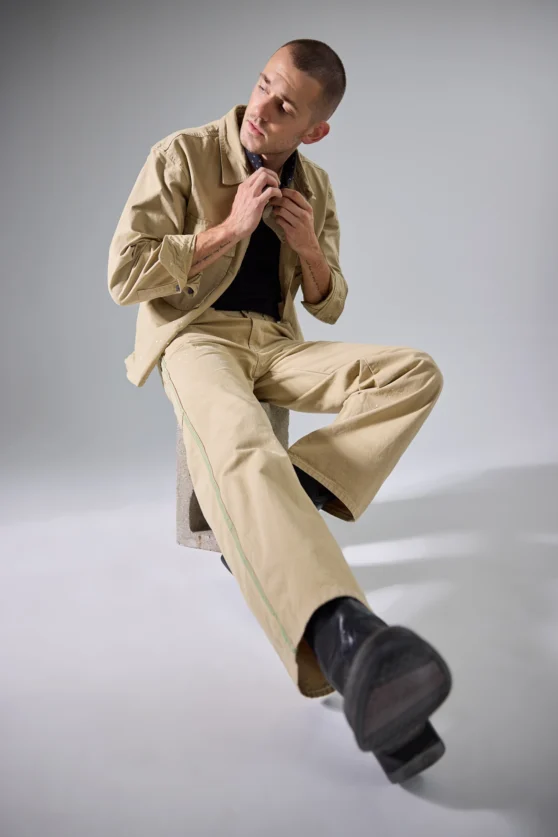 Editorial fashion movement shot with shirtless model in white pants, styled for contemporary fashion brands.