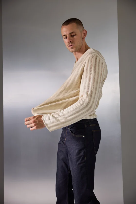 Monochrome fashion shot of male model sitting cross-legged wearing boots and cropped trousers for editorial brand campaign.