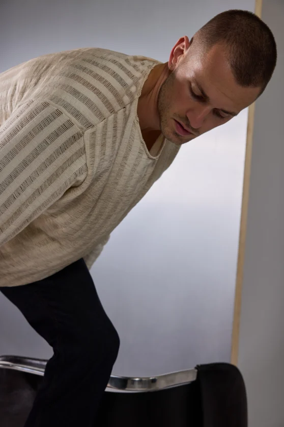 Male model jumping mid-air in black pants and shirtless for energetic modern fashion editorial.