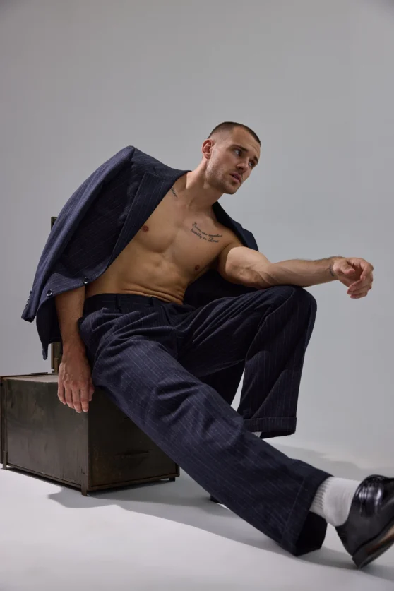 Model in expressive pose wearing white pants in fashion editorial aimed at commercial clients.