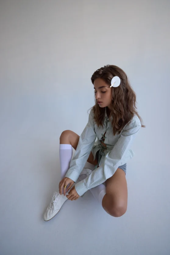 Model posing on the floor in light wardrobe, styled for fashion campaign