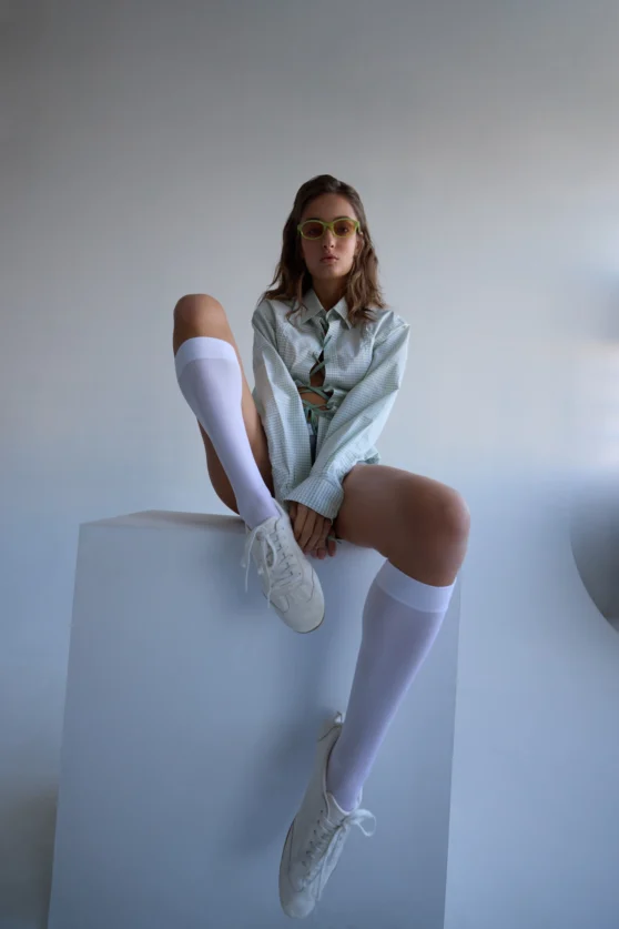 Fashion model in light blue shirt and knee-high socks posing editorial-style