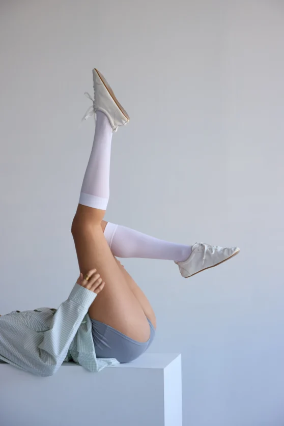 E-commerce photo showcasing white boots and knee-high socks against minimal background