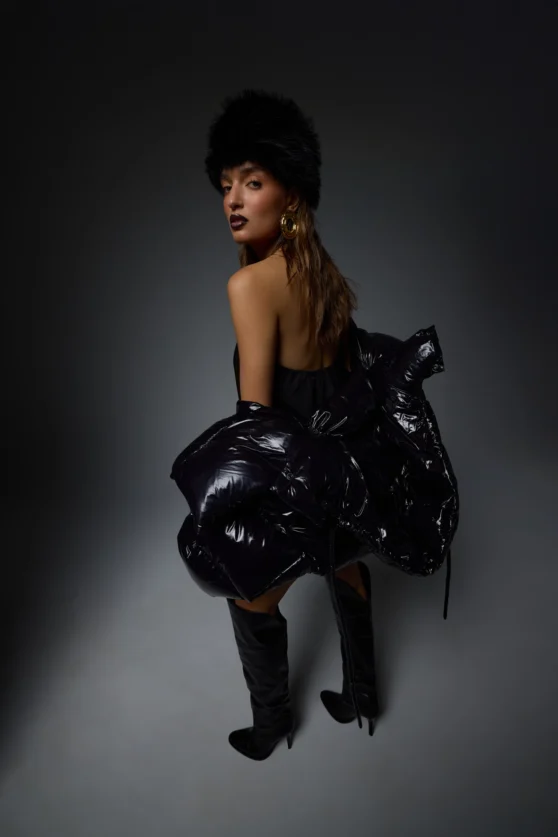 Side view of model wearing glossy black puffer jacket styled for fashion lookbook