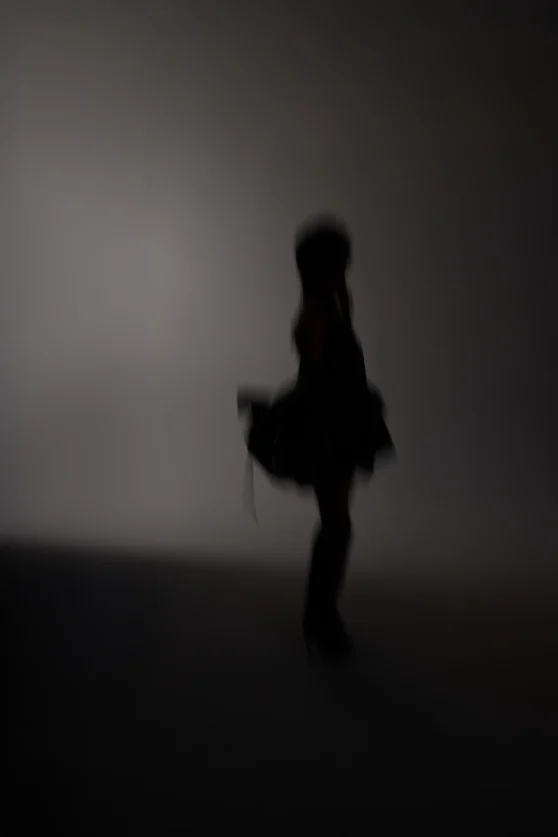 Stylized silhouette image of model walking in motion blur against neutral backdrop