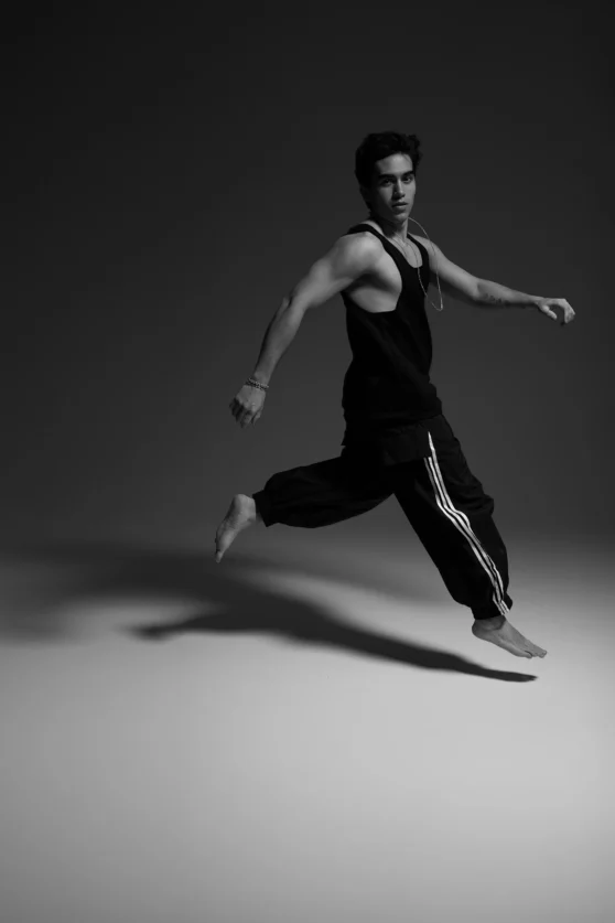 Black-and-white fashion portrait of Kalet Samuel Ponce de León in motion, wearing a sleeveless black top and cropped pants, photographed in studio by Igor Momot.